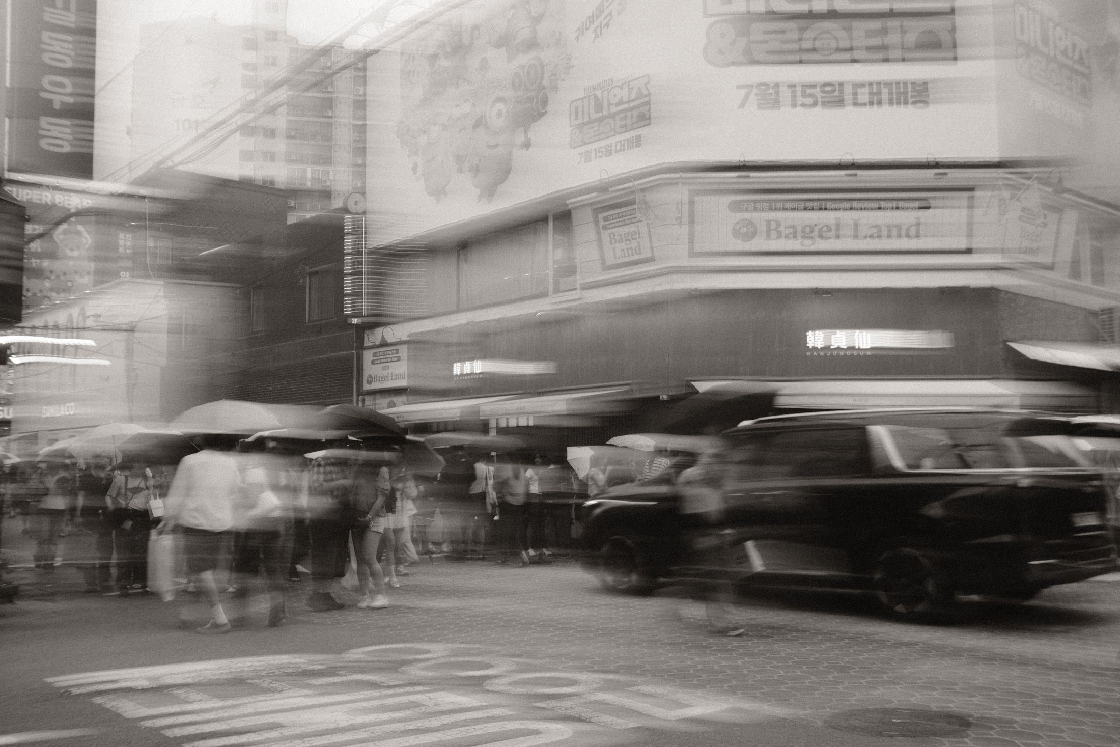 Long-exposure street crossing with umbrellas