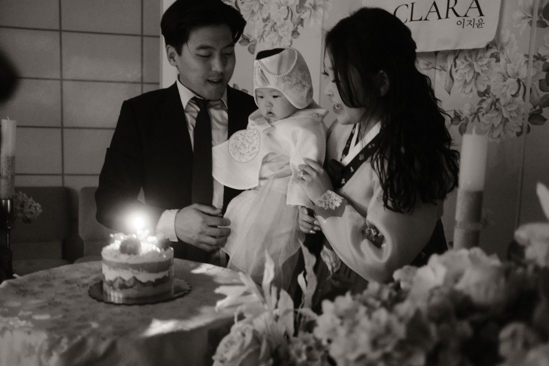 Family over a cake with a single candle, black and white