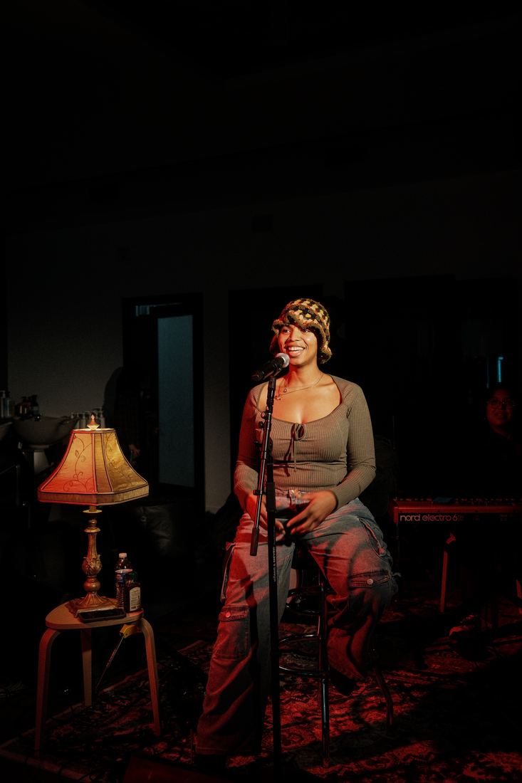 Singer standing beside a table lamp on a patterned rug
