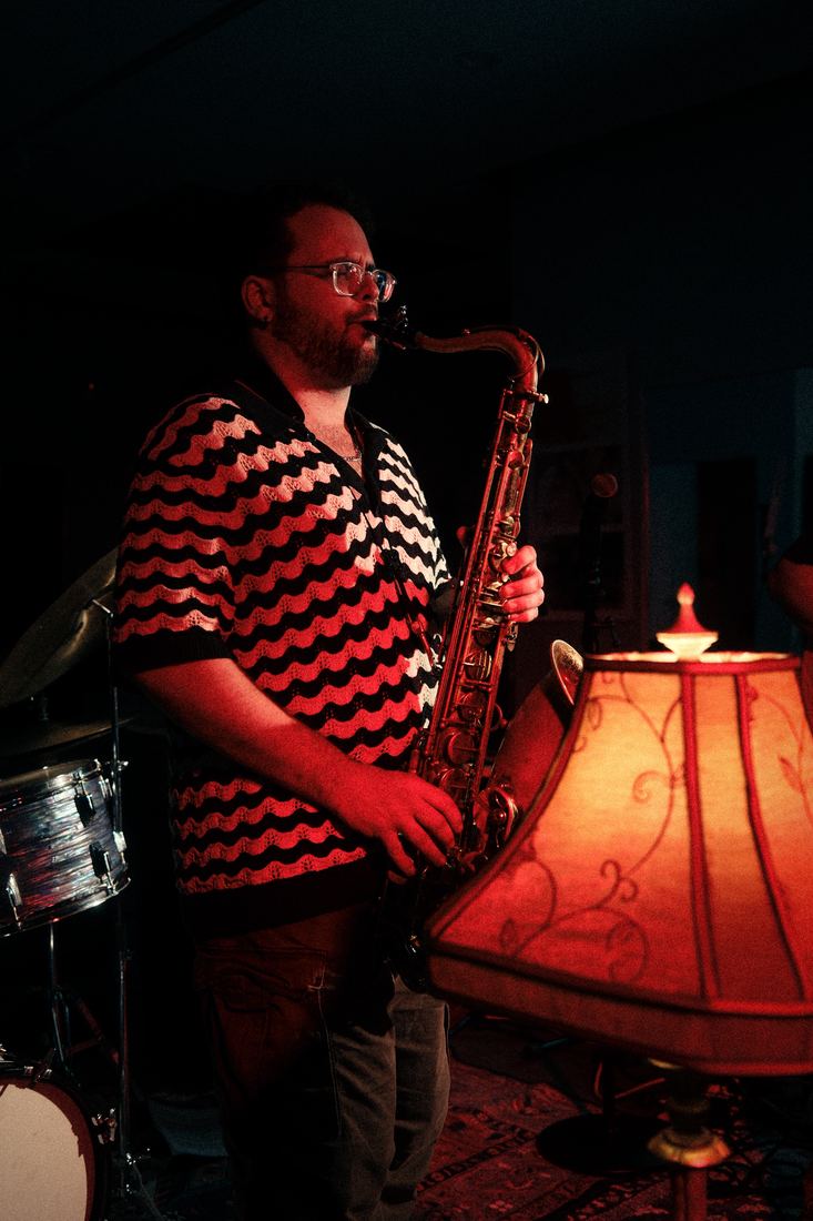 Saxophonist beside a glowing lamp