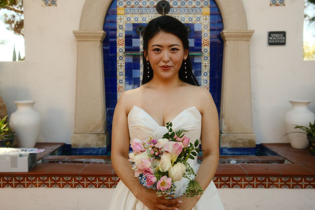 Bride holding her bouquet in front of a tiled fountain
